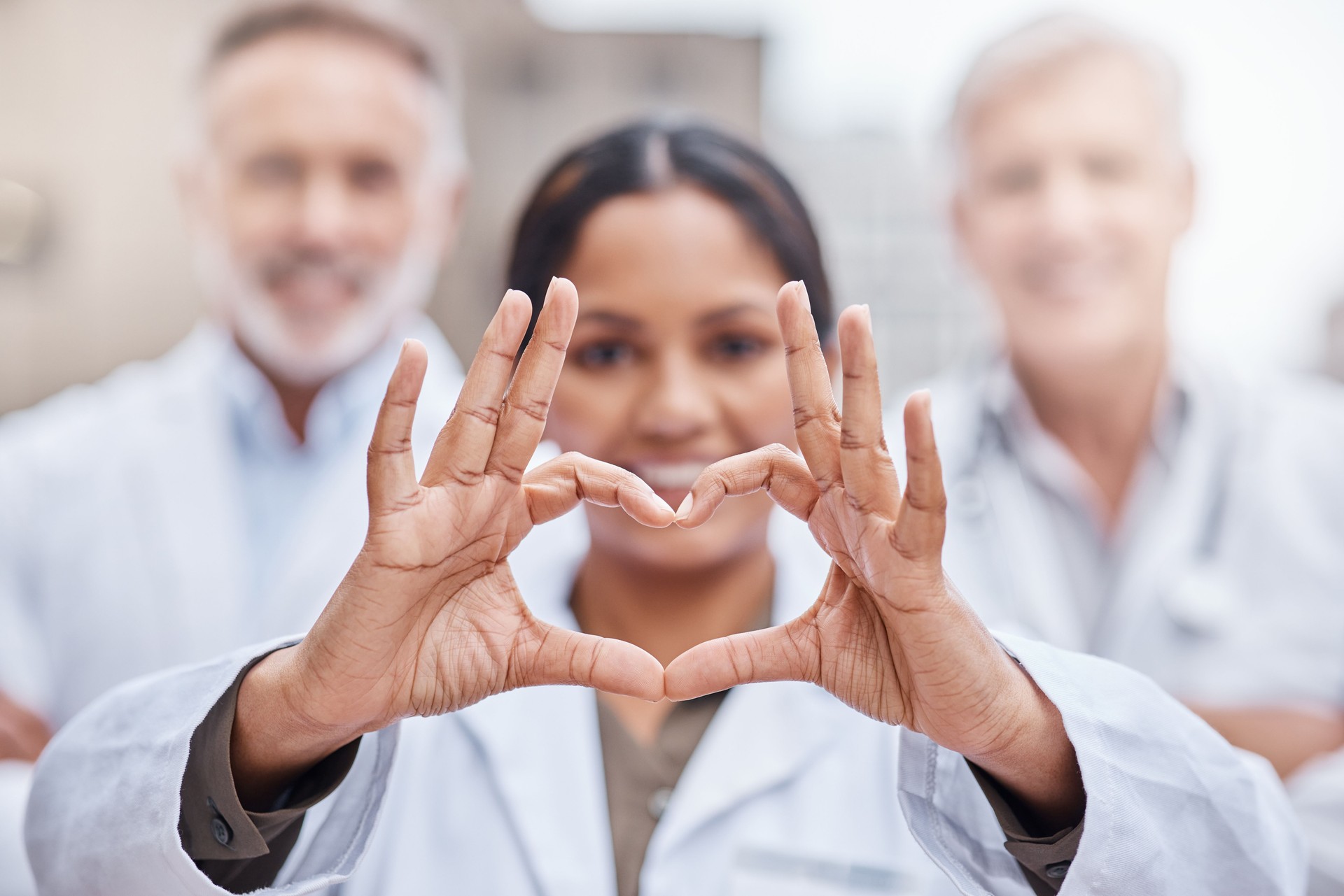 Shot of a young female doctor making a heart shape with her hands while standing in the city