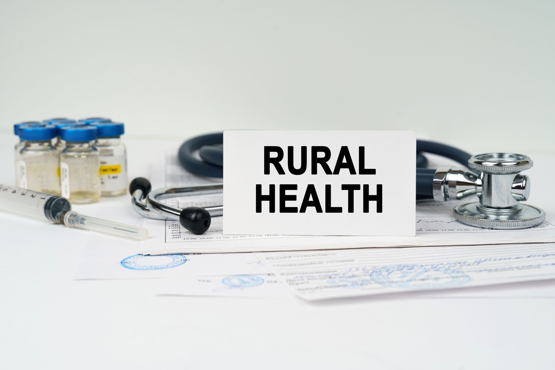 On the medical documents there is a stethoscope, syringe and a business card with the inscription - rural health